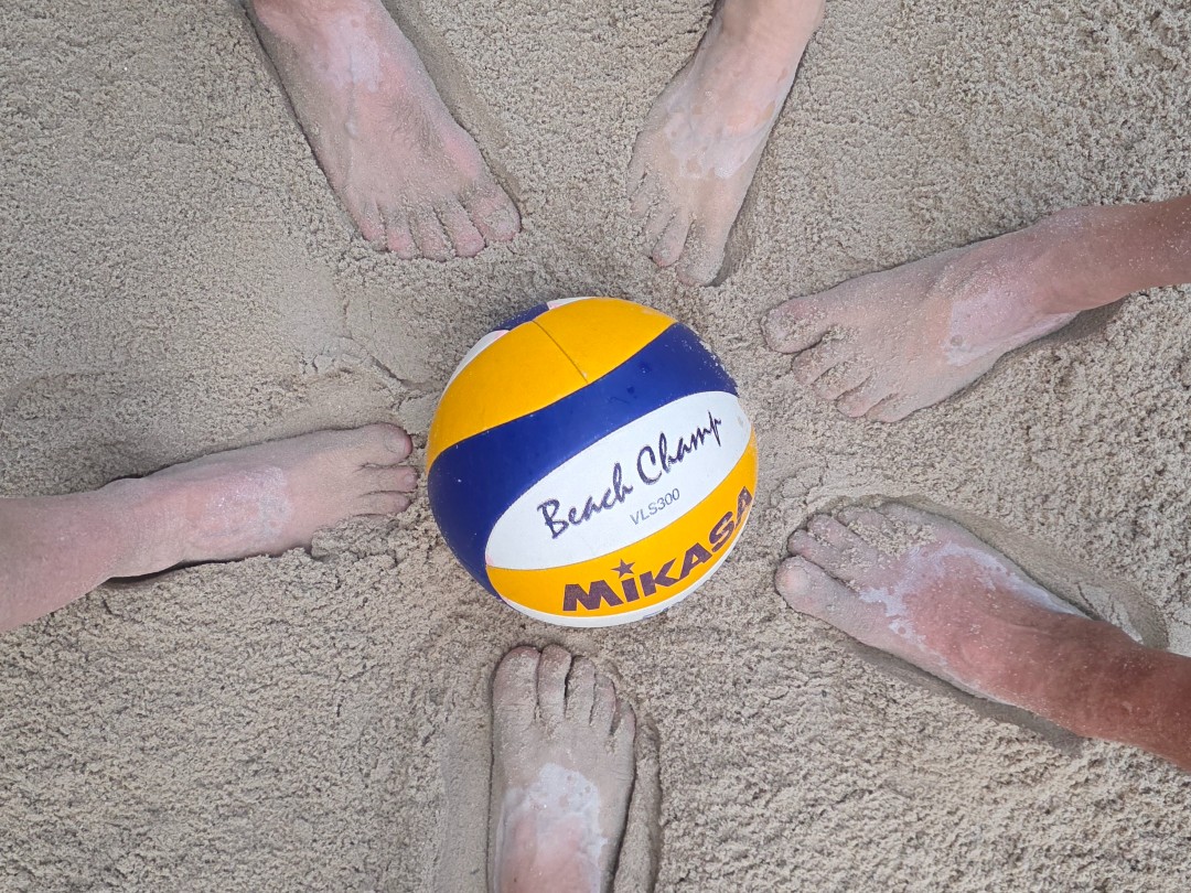 Volleyball mit Füssen im Sand